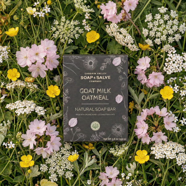 Goat Milk Oatmeal natural soap bar from Orchard Valley Soap & Salve Company surrounded by wildflowers.