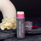 natural vegan lip balm stick displayed on slate with dried flowers in background.